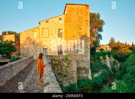 France, Aude, Parc naturel régional des Corbières Fenouilledes, Castel des Corbières, jeune femme sur un pont médiéval bénéficiant de la vue, dans un village médiéval au lever du soleil Banque D'Images