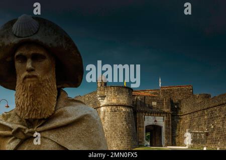 France, Pyrénées Atlantiques, Béarn, Navarrenx, sculpture d'un pèlerin sur le chemin de Saint Jacques devant les remparts d'une ville sous un ciel orageux Banque D'Images