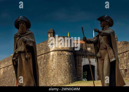 France, Pyrénées Atlantiques, Béarn, Navarrenx, sculptures de pèlerins sur le chemin de Saint Jacques devant les remparts d'une ville sous un ciel orageux Banque D'Images