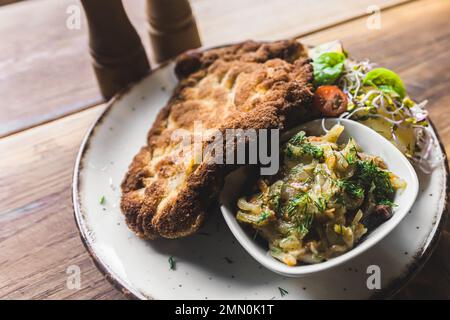 Vue de haut en bas de la panée côtelette de porc frite schabowy avec pommes de terre bouillies et salade servi sur une assiette blanche. Cuisine polonaise. Prise de vue horizontale en intérieur. Photo de haute qualité Banque D'Images