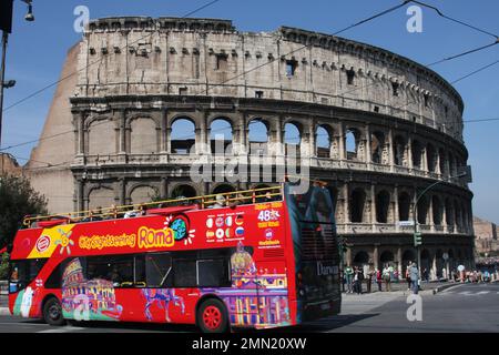 Italie, Rome. Le bus touristique passe devant le Colisée, l'arène antique. Banque D'Images