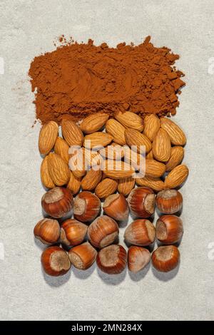 Noix, fèves de cacao et sucre sur fond gris pierre. Composition au chocolat. Banque D'Images