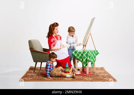 Passe-temps. Belle femme, mère jouant avec ses fils, apprenant et dessinant des peintures ensemble. Prendre soin des enfants Banque D'Images