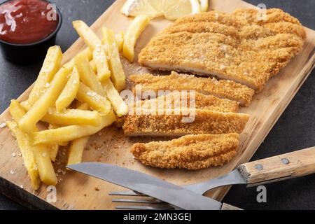 Schnitzel Wiener avec pommes de terre frites sur fond noir Banque D'Images