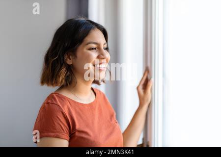 Portrait de la jeune femme arabe debout près de la fenêtre à la maison Banque D'Images