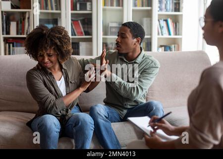 Homme africain essayant de calmer la femme pleurant, séance de thérapie Banque D'Images