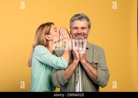 Potins, partagez des conseils. Femme chuchotant à son mari à l'oreille, heureux surpris homme écoutant la femme Banque D'Images
