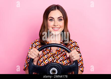 Photo de jeune positive optimiste nouveau propriétaire de voiture dame brun cheveux tenir le volant expert chauffeur de taxi isolé sur fond rose pastel Banque D'Images