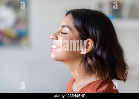 Photo de profil de la jeune femme arabe ravie souriant avec les yeux fermés Banque D'Images