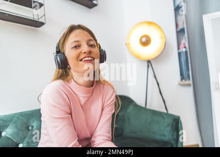 Une jeune femme souriante écoute de la musique avec un casque d'écoute. Photo de haute qualité Banque D'Images
