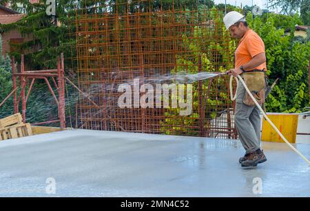 Travailleur de la construction de béton frais d'arrosage à l'aide d'un flexible Banque D'Images