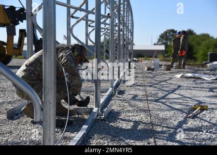 Sgt. Maître Jack Fergun serre un tendeur sur un câble attaché à une structure en tissu de tension en construction pour l'école secondaire Woodbine, Iowa, sur 28 septembre 2022. Les aviateurs de l’Escadron de génie civil de l’Escadre de ravitaillement aérien 185th de la Garde nationale de l’Iowa Air ont été invités à contribuer à la construction de la structure donnée qui sera utilisée pour accueillir les personnes du DOD voyageant à Woodbine, prenant part à un projet novateur de construction de l’instruction de préparation ici au cours des prochains mois. U.S. Air National Guard photo Sgt. Vincent de Groot Banque D'Images