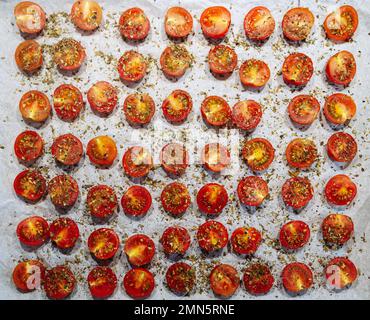 Faire cuire des tomates séchées, des morceaux de tomates cerises avec des herbes et des épices sur la plaque de cuisson vue en grand angle. Banque D'Images
