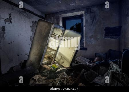 Réfrigérateur abandonné avec lumière brillant dans la chambre remplie de déchets, Pennsylvanie, États-Unis Banque D'Images