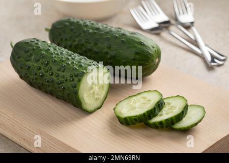 En gros plan sur un tableau de découpe, le concombre de snack sain frais entier et en tranches, Marketmore Banque D'Images