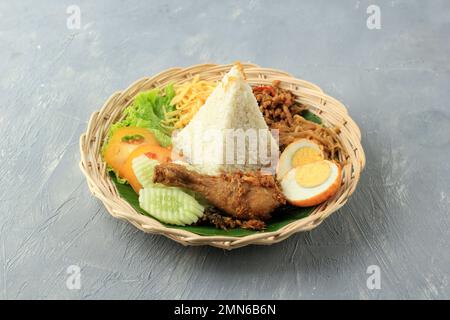 Nasi Uduk Tumpeng, riz cuit à la vapeur salé au lait de coco, servi avec divers plats d'accompagnement. Populaire pour le petit déjeuner Banque D'Images
