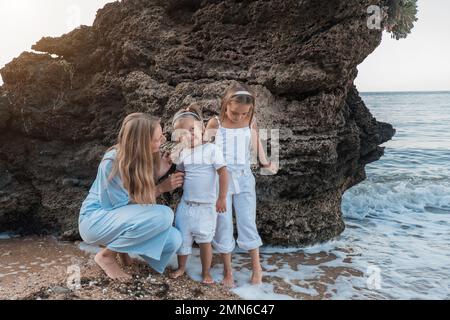 L'amour de la mère. Maman embrasse ses filles, embrasse et joue, tendresse et soin. Famille sympathique à la maison et en vacances. Banque D'Images