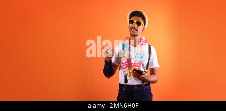 Déguisement brésilien de carnaval. Black Man avec Carnival Costume Holding Mobile, isolé sur fond orange Banque D'Images