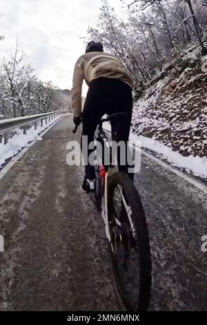 Les cyclistes se promène sur une route de montagne enneigée Banque D'Images
