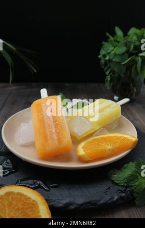 des pop-sicles jaune et orange sur une plaque blanche Banque D'Images