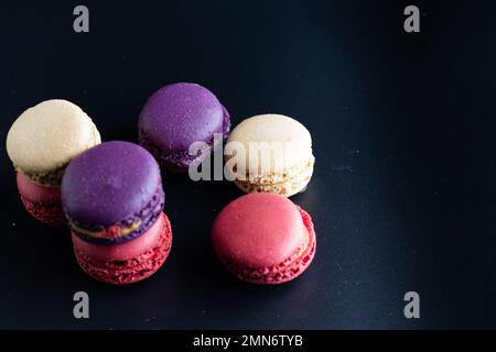 mini macaron de couleur différente sur fond sombre Banque D'Images