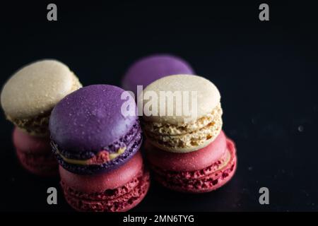 mini macaron de couleur différente sur fond sombre Banque D'Images