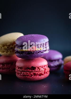 mini macaron de couleur différente sur fond sombre Banque D'Images