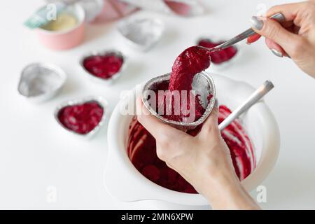 Boulanger cuisinant des petits gâteaux en velours rouge en forme de coeur. Banque D'Images