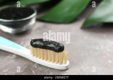 Brosse à dents à poils naturels et pâte de charbon sur table en marbre gris, gros plan Banque D'Images
