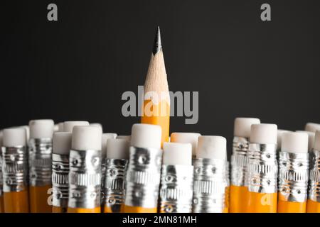 Un crayon avec un point vif se faisant remarquer des autres sur fond noir, gros plan Banque D'Images