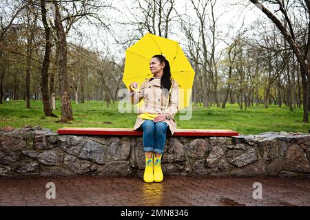Faire face au stress et à l'anxiété. Pratiquer la pleine conscience et les techniques de relaxation. Bonne femme âgée sous un manteau de pluie jaune avec parasol jaune marchant Banque D'Images