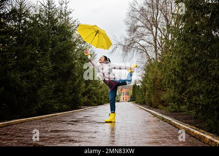 Faire face au stress et à l'anxiété. Pratiquer la pleine conscience et les techniques de relaxation. Bonne femme âgée sous un manteau de pluie jaune avec parasol jaune marchant Banque D'Images