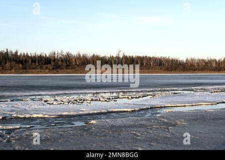 Restes de la dernière glace de printemps sur la rivière près de l'eau libre et de la forêt. Banque D'Images