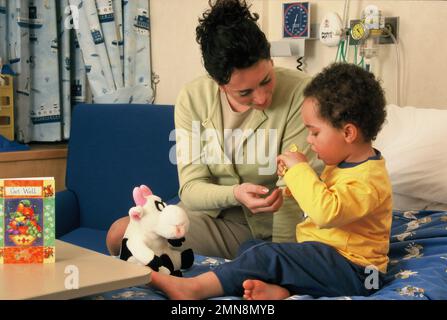 Style de vie. Soins de santé. Femme assise sur le lit de l'hôpital avec un garçon enfant. Banque D'Images