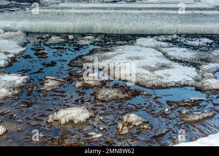 Les restes de la dernière glace printanière sur la rivière fondent près de la rive dans l'eau. Banque D'Images