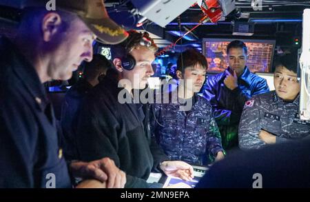 EAUX À L'EST DE LA PÉNINSULE CORÉENNE (SEPT 30, 2022) Cmdr. Marcus Seeger, à gauche, commandant du destroyer à missiles guidés de classe Arleigh Burke USS Benfold (DDG 65), Lt. j.g. Bill Watkins, au centre à gauche, de l'Université Lincoln, en Pennsylvanie, marin de la Force d'autodéfense maritime japonaise, lieutenant j. g. Le Lt Aaron Van Driessche, au centre à droite, de Simi Valley, en Californie, et le Lt Taehyung Kim, à droite, marin de la marine de la République de Corée, surveillent les contacts de surface simulés au cours d’un exercice trilatéral de guerre anti-sous-marine dans le centre d’information de combat du navire, septembre 30. Benfold et Carrier Banque D'Images