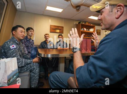 EAUX À L'EST DE LA PÉNINSULE CORÉENNE (SEPT 30, 2022) Cmdr. Marcus Seeger, à droite, commandant du destroyer de missile guidé de classe Arleigh Burke USS Benfold (DDG 65), Ensign Filemoni Leti Filemoni, au centre à droite, de San Diego, Lt. j.g. Bill Watkins, au centre, de l'Université Lincoln, en Pennsylvanie, marin de la Force d'autodéfense maritime japonaise, lieutenant j. g. RVou Kato, au centre à gauche, et le lieutenant Taehyung Kim, marin de la marine de la République de Corée, à gauche, discutent des opérations trilatérales et des relations dans le bureau du commandant, le 30 septembre. Benfold, et Carrier Strike Group (CSG) 5, mène un tri-latéral anti-s. Banque D'Images