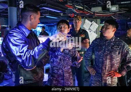 EAUX À L'EST DE LA PÉNINSULE CORÉENNE (SEPT 30, 2022) Lt Aaron Van Driessche, à gauche, de Simi Valley, Californie, marin de la Force d'autodéfense maritime japonaise Lt J. g. RVou Kato, centre gauche, Cmdr. Marcus Seeger, au centre-droit, commandant du destroyer de missiles guidés de classe Arleigh Burke USS Benfold (DDG 65), et du marin de la République de Corée, le lieutenant Taehyung Kim, à droite, discutent des similitudes entre les systèmes de combat lors d’un exercice trilatéral de guerre anti-sous-marine dans le centre d’information de combat du navire, le 30 septembre. Benfold, et Carrier Strike Group (CSG) 5, mène un anti-submar trilatéral Banque D'Images