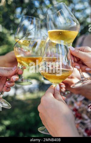 Faire un toast de fête avec du vin mousseux. Les mains des femmes tiennent des verres de champagne. Concept anniversaire, vacances, fête et amitié. Banque D'Images