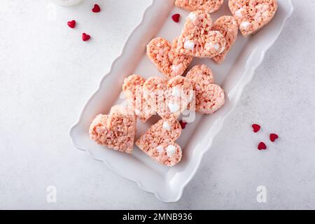 Gâteries en forme de coeur de riz rose pour la Saint-Valentin sur une assiette avec coeur rouge saupoudrés Banque D'Images