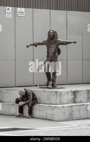 Sam Man assis devant la statue de sculpture de Happy Bob Marley à Liverpool, Royaume-Uni Banque D'Images