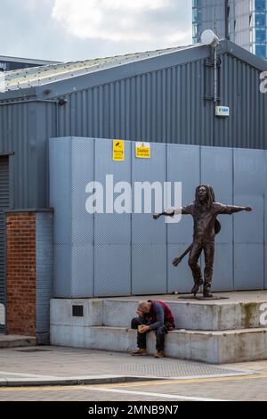 Sam Man assis devant la statue de sculpture de Happy Bob Marley à Liverpool, Royaume-Uni Banque D'Images