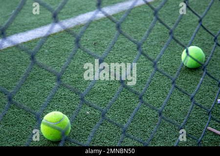 balles de tennis sur un terrain de paddle en herbe artificielle vu derrière une clôture Banque D'Images