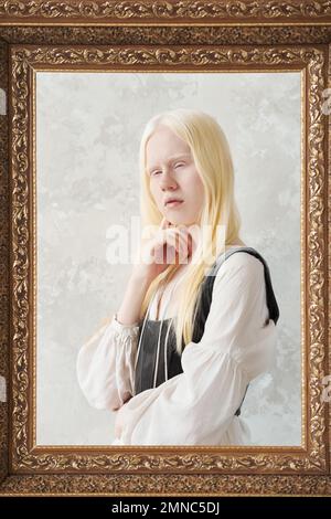 Grand cadre photo avec sereine albino fille derrière posant devant l'appareil photo contre le mur blanc pendant la séance photo en studio Banque D'Images