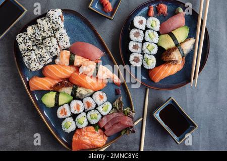 La gamme de différents types de sushis, de rouleaux et de Maki avec sauces et baguettes. Sur fond rustique Banque D'Images
