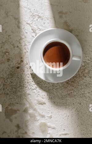 Boisson au cacao dans une tasse blanche sur fond blanc d'argile texturée, vue du dessus Banque D'Images
