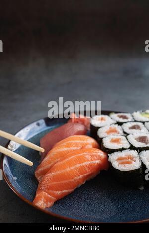 Délicieux petits pains à sushis servis sur une table rustique avec des baguettes Banque D'Images