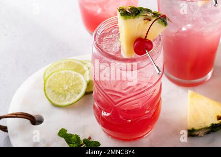 Cocktail Singapore Sling dans une variété de verres garni d'ananas et de cerise Banque D'Images