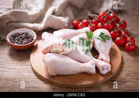 des cuisses de poulet fraîches avec du persil et des épices sur une planche de bois Banque D'Images