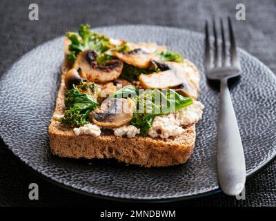 Ricotta végétalien maison, champignons et Kale sur le pain grillé Banque D'Images